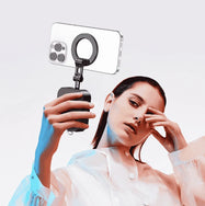 A model holding the extended phone stand as a selfie stick or vlogging grip, with a smartphone mounted horizontally for stable video recording or photography.